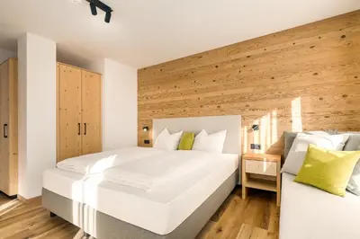a bedroom with two beds and a wooden wall at Neuhuberhof in Vols am Schlern