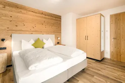 a white bed in a room with a wooden wall at Neuhuberhof in Vols am Schlern