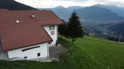 a white building with a red roof on a green field at Portnerhof auf Oberkirn in Schenna