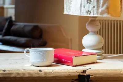 a table with a coffee cup and a book and a lamp at Ciasa Gianot - Shin in Moena