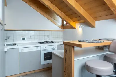 a kitchen with white appliances and wooden ceilings at Ciasa Gianot - Shin in Moena