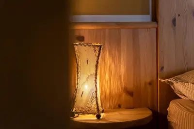 a lamp with a net on a wall next to a bed at Ciasa Gianot - Shin in Moena