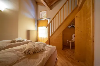 two beds in a room with wooden floors and a staircase at Ciasa Gianot - Shin in Moena