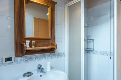 a bathroom with a sink and a mirror and a shower at Ciasa Gianot - Shin in Moena