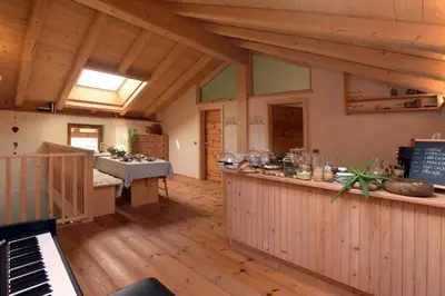 a large room with a piano and a kitchen at B&B Mas de Lagorae in Tesero
