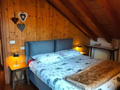 a bedroom with a bed with a wooden wall at Deliziosa mansarda con vista Dolomiti in San Vito di Cadore