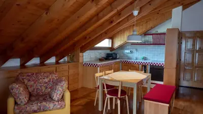 a kitchen with a table and a chair in a room at Deliziosa mansarda con vista Dolomiti in San Vito di Cadore
