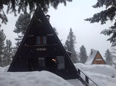 a black cabin with snow on the ground at Baita Giggia sulle piste - Cavalese in Trentino Alto Adige cottage chalet in Cavalese