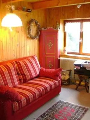 a living room with a red couch and a piano at Baita Giggia sulle piste - Cavalese in Trentino Alto Adige cottage chalet in Cavalese