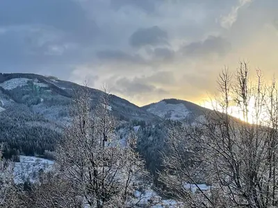 a view of a snowy mountain with trees and the sunset at Apartment LUNA in Tesero