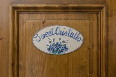 a sign on a wooden door with flowers on it at Sweet Cristallo in Cortina dʼAmpezzo