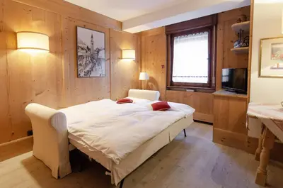 a bedroom with a large bed and a television at Sweet Cristallo in Cortina dʼAmpezzo