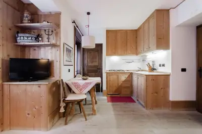 a kitchen with wooden cabinets and a table and a television at Sweet Cristallo in Cortina dʼAmpezzo
