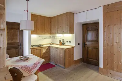 a kitchen with wooden cabinets and a table in it at Sweet Cristallo in Cortina dʼAmpezzo