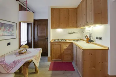 a kitchen with wooden cabinets and a table in it at Sweet Cristallo in Cortina dʼAmpezzo