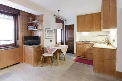 a kitchen with wooden cabinets and a table with a sink at Sweet Cristallo in Cortina dʼAmpezzo