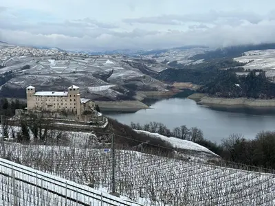 a castle on a hill next to a river at Val di Non Apartment in Cles