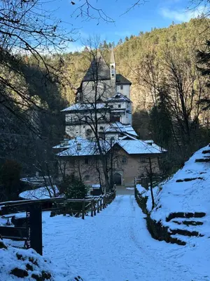 a large building in the middle of a snow covered yard at Val di Non Apartment in Cles