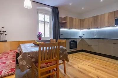a kitchen with a table and a dining room at DolomiApartments - Appartamenti Campanil 1 e Campanil 2 in Predazzo