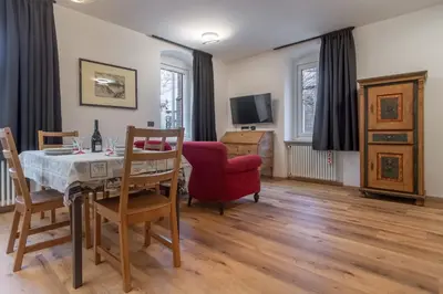 a dining room with a table and a red chair at DolomiApartments - Appartamenti Campanil 1 e Campanil 2 in Predazzo