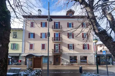 a large pink building with red and blue windows at DolomiApartments - Appartamenti Campanil 1 e Campanil 2 in Predazzo