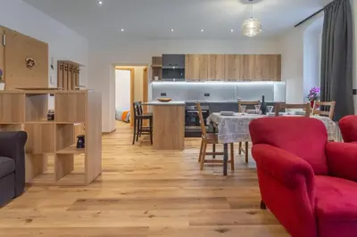 a living room and kitchen with a table and chairs at DolomiApartments - Appartamenti Campanil 1 e Campanil 2 in Predazzo