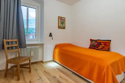 a bedroom with a bed and a chair and a window at DolomiApartments - Appartamenti Campanil 1 e Campanil 2 in Predazzo