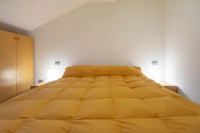 a large yellow bed in a white room at DolomiApartments - Appartamento Orso Bruno in Predazzo
