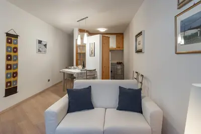 a living room with a white couch and a kitchen at DolomiApartments - Appartamento Orso Bruno in Predazzo