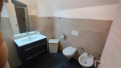a bathroom with a sink and a toilet and a mirror at In centro col giardino in Predazzo
