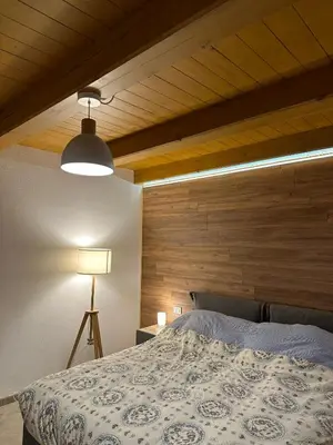a bedroom with a bed with a wooden wall at Tabia Suite Pelmo in Villagrande