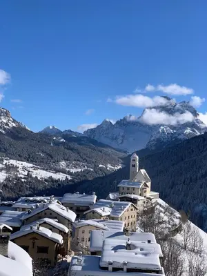 a town in the snow with mountains in the background at Tabia Suite Pelmo in Villagrande
