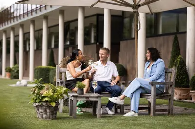 a group of people sitting on benches under an umbrella at Solterra Poolhouse 1 in Tesimo