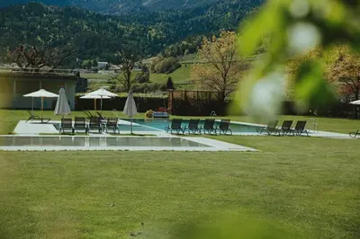 a pool with chairs and umbrellas in a park at Solterra Poolhouse 1 in Tesimo
