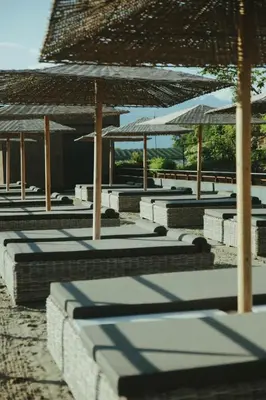 a row of lounge chairs with umbrellas on a beach at Solterra Poolhouse 1 in Tesimo