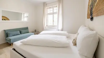 a bedroom with two beds and a couch and a window at Italyescapes Emma 22 in Merano