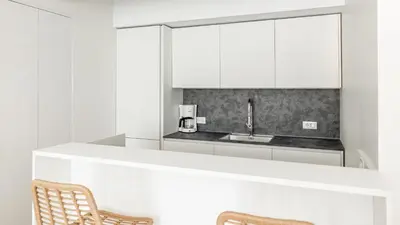 a kitchen with white cabinets and a sink and two chairs at Italyescapes Emma 22 in Merano