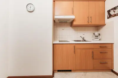 a kitchen with wooden cabinets and a clock on the wall at Gästehaus Marianne Terenten in Terento
