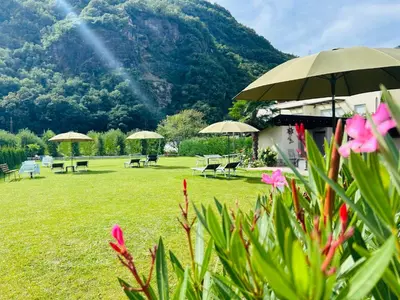 a garden with tables and umbrellas and a mountain at Rosalie Apartments in Lana