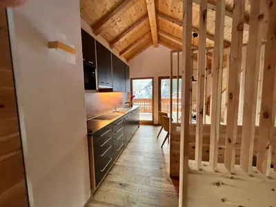 a kitchen with black cabinets and a wooden floor at Lüch dl Finatzer in San Martino in Badia