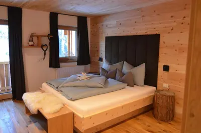 a bedroom with a large bed with a wooden wall at Lüch dl Finatzer in San Martino in Badia