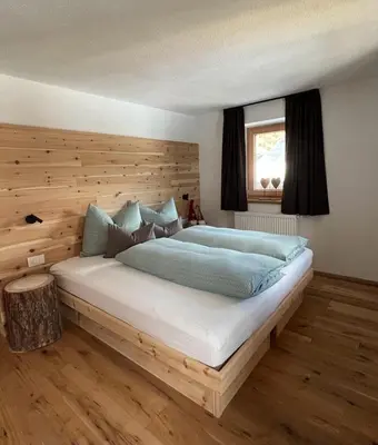 a bedroom with a large bed with a wooden headboard at Lüch dl Finatzer in San Martino in Badia