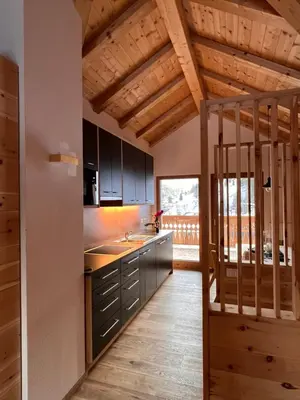 a kitchen with black cabinets and a wooden ceiling at Lüch dl Finatzer in San Martino in Badia