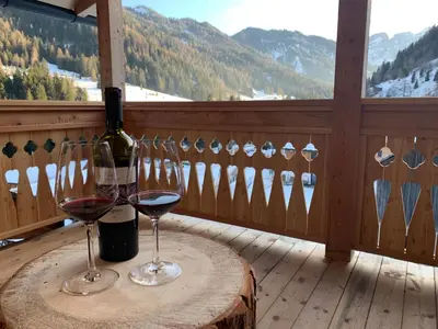 a table with two glasses of wine on a balcony at Lüch dl Finatzer in San Martino in Badia