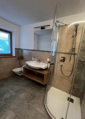 a bathroom with a sink and a shower and a toilet at Lüch dl Finatzer in San Martino in Badia