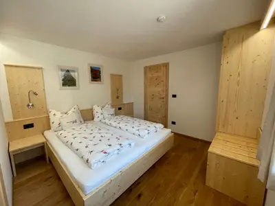 a bedroom with a large white bed and wooden floors at Neuhäusl-Hof in San Genesio Atesino
