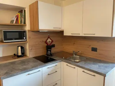 a kitchen with white cabinets and a sink and a microwave at Neuhäusl-Hof in San Genesio Atesino