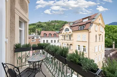 a balcony with a table and chairs and buildings at Meranosuites in Merano