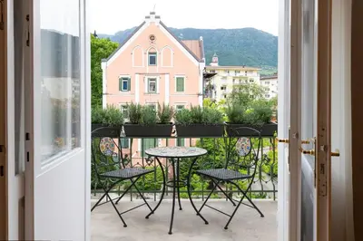 a balcony with a table and chairs and a building at Meranosuites in Merano