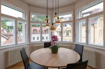 a dining room with a table and chairs and windows at Meranosuites in Merano